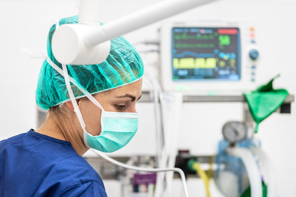 Woman in mouth guard and hair net in operating room.