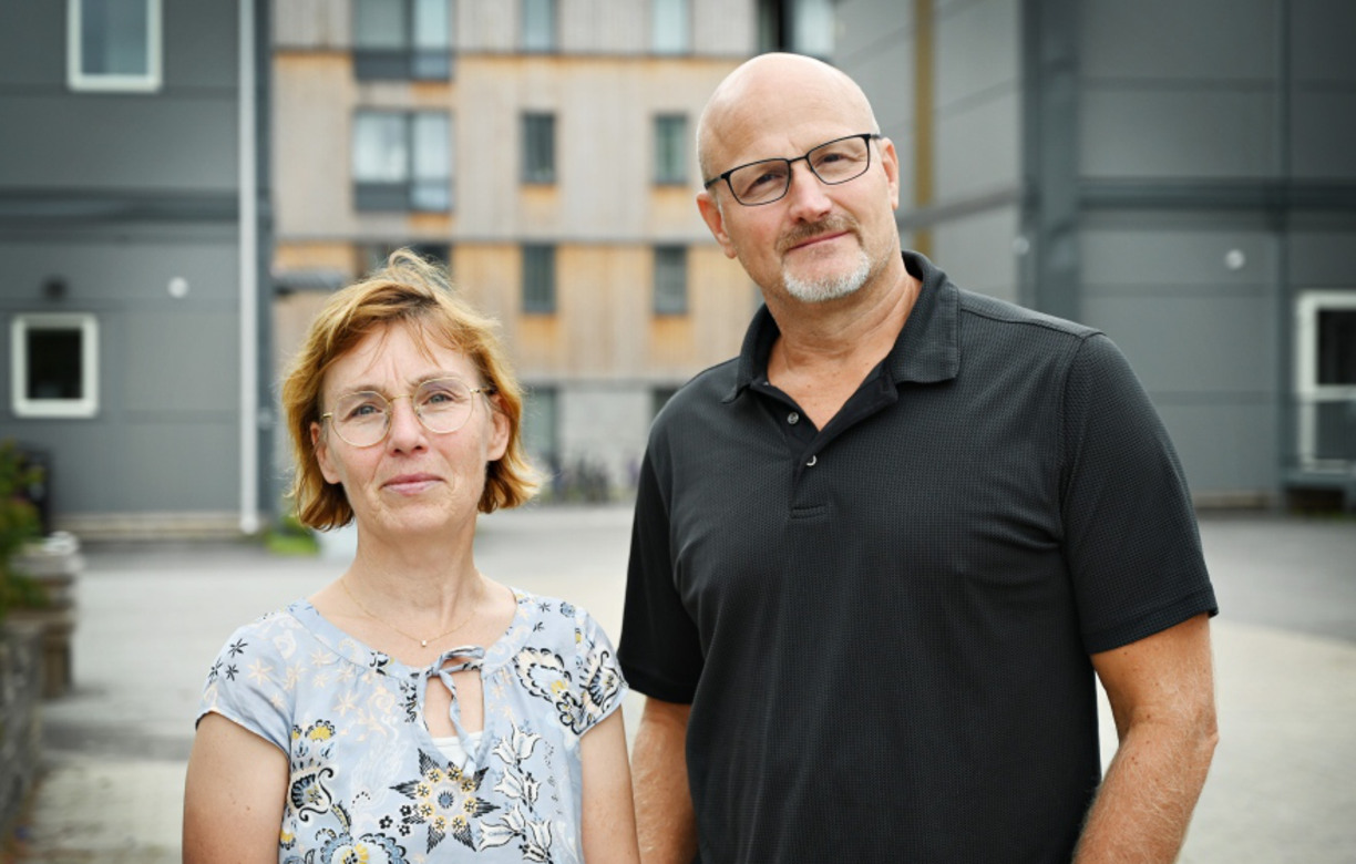 Johanna Sundbaum and Phillip Tretten stand outside and look into the camera and smile, in the background buildings and greenery are visible.