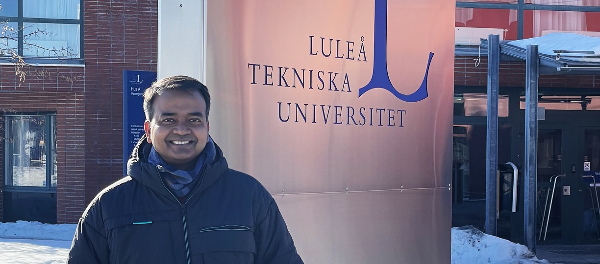 A man standing infront of a Luleå University of Technology sign