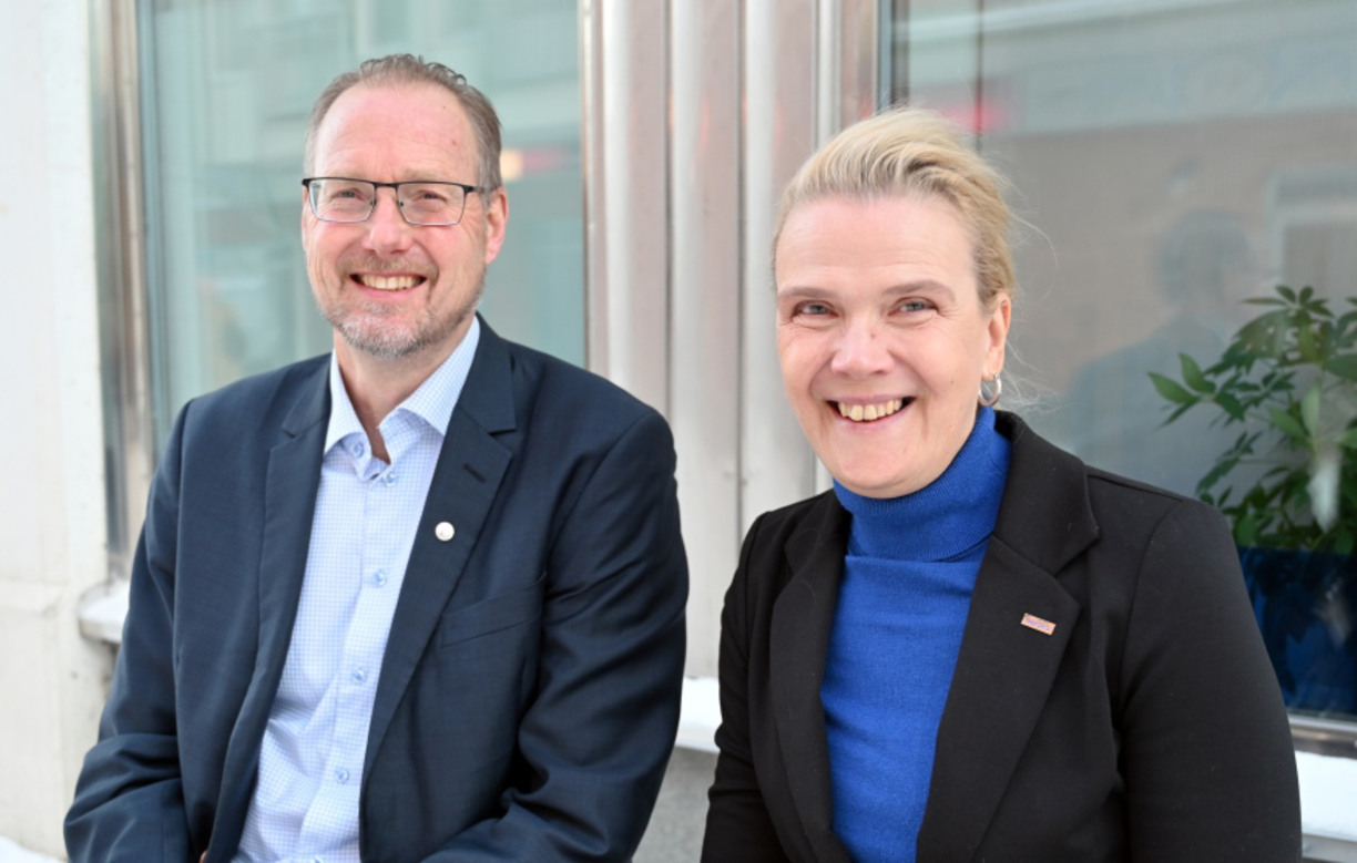 Staffan Lundström and Anna Edin sit next to each other and smile at the camera in the background two windows and a flower