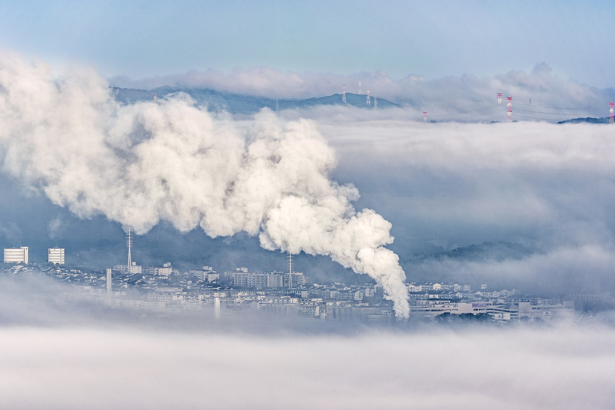 An industrial area surrounded by clouds and water vapor from a factory chimney
