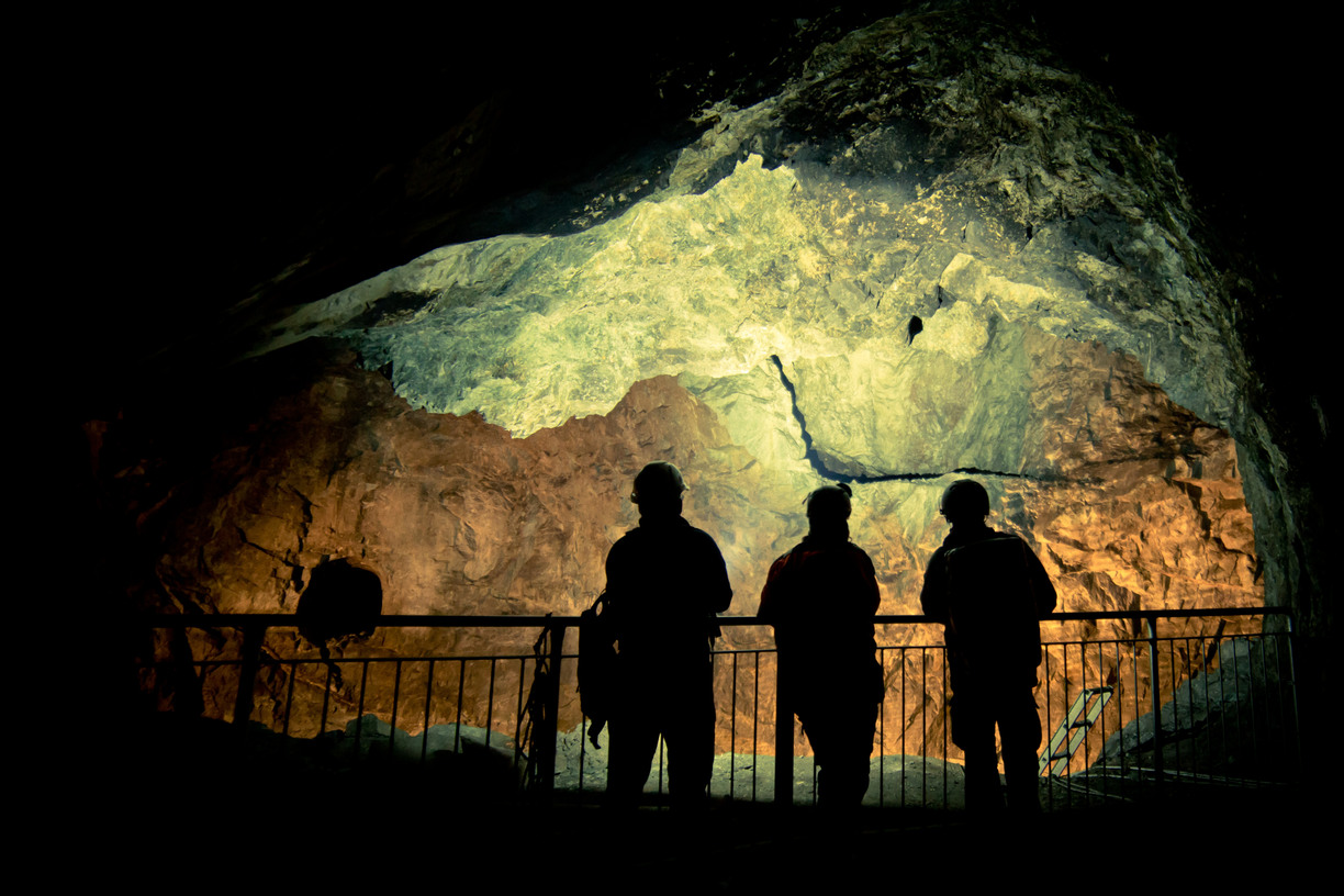 Silhouettes of three miners against an illuminated mine wall