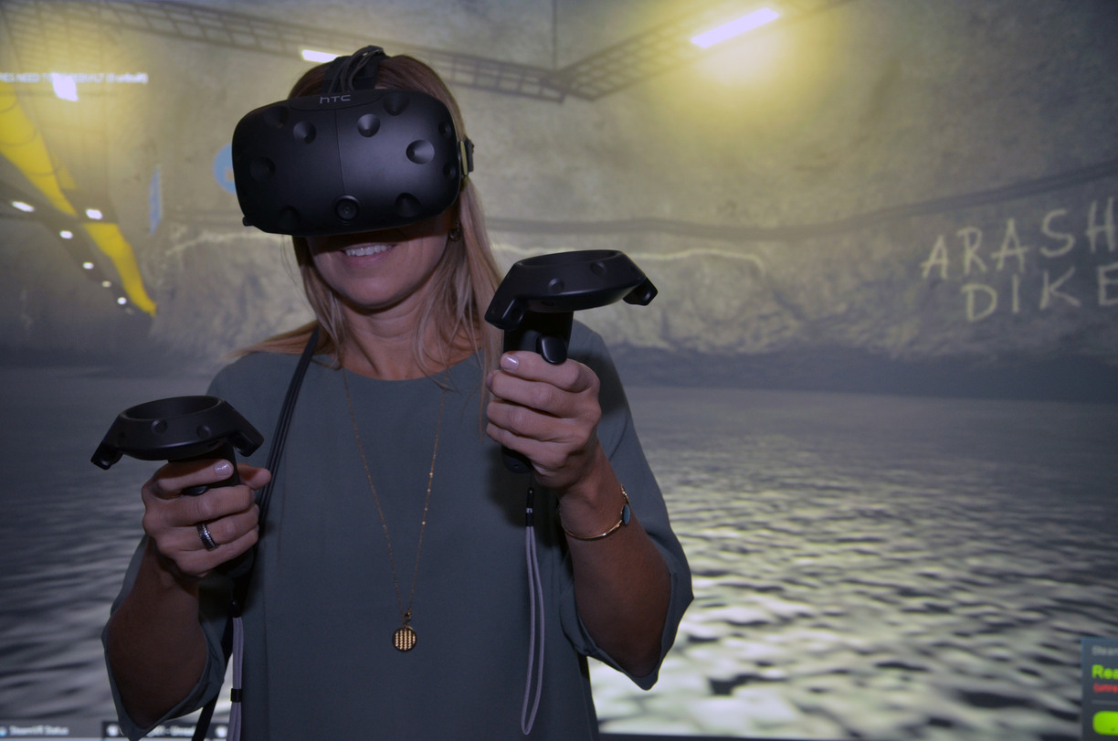 Person wearing VR-glasses in front of a background of a virtual mine