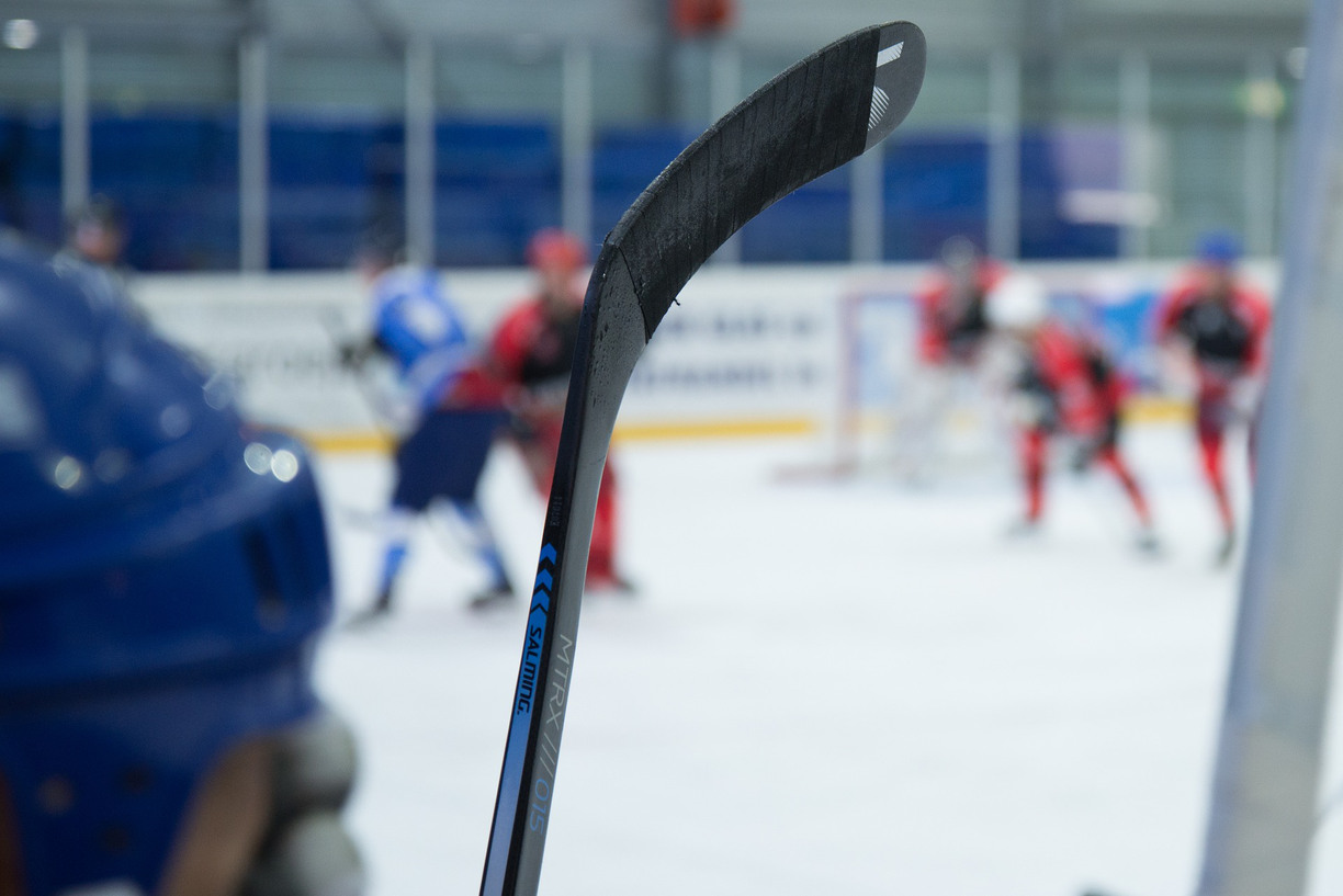 En hockeyklubba i fokus, framför en bakgrund av hockeyspelare på isen