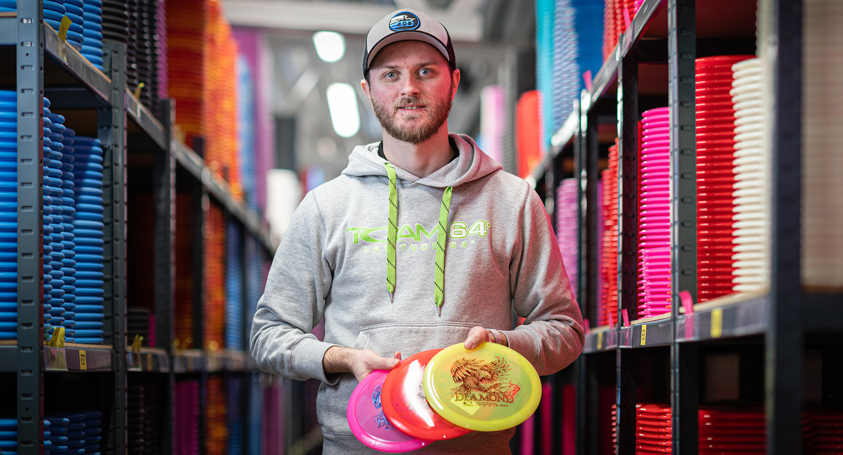 Man standing in warehouse holding several discs for disc golf