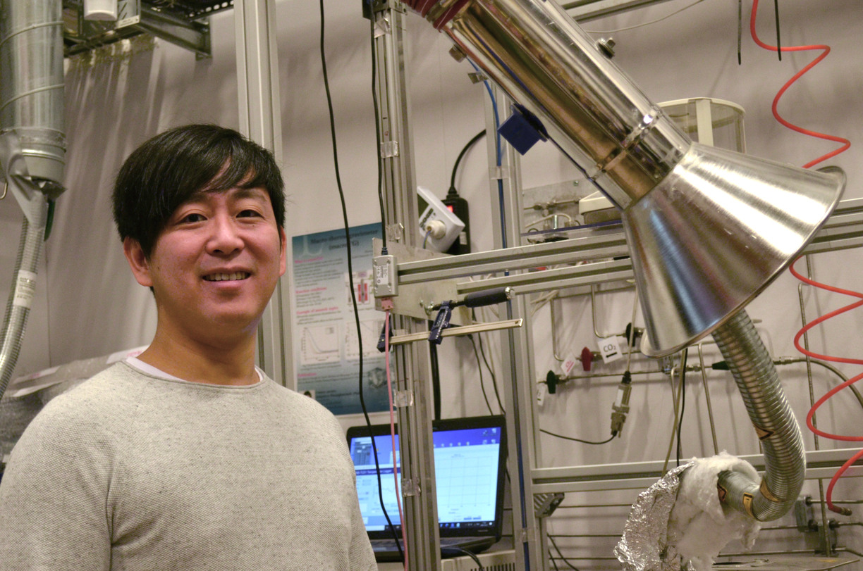 Kentaro Umeki tittar mot kameran och ler, stående i labbet