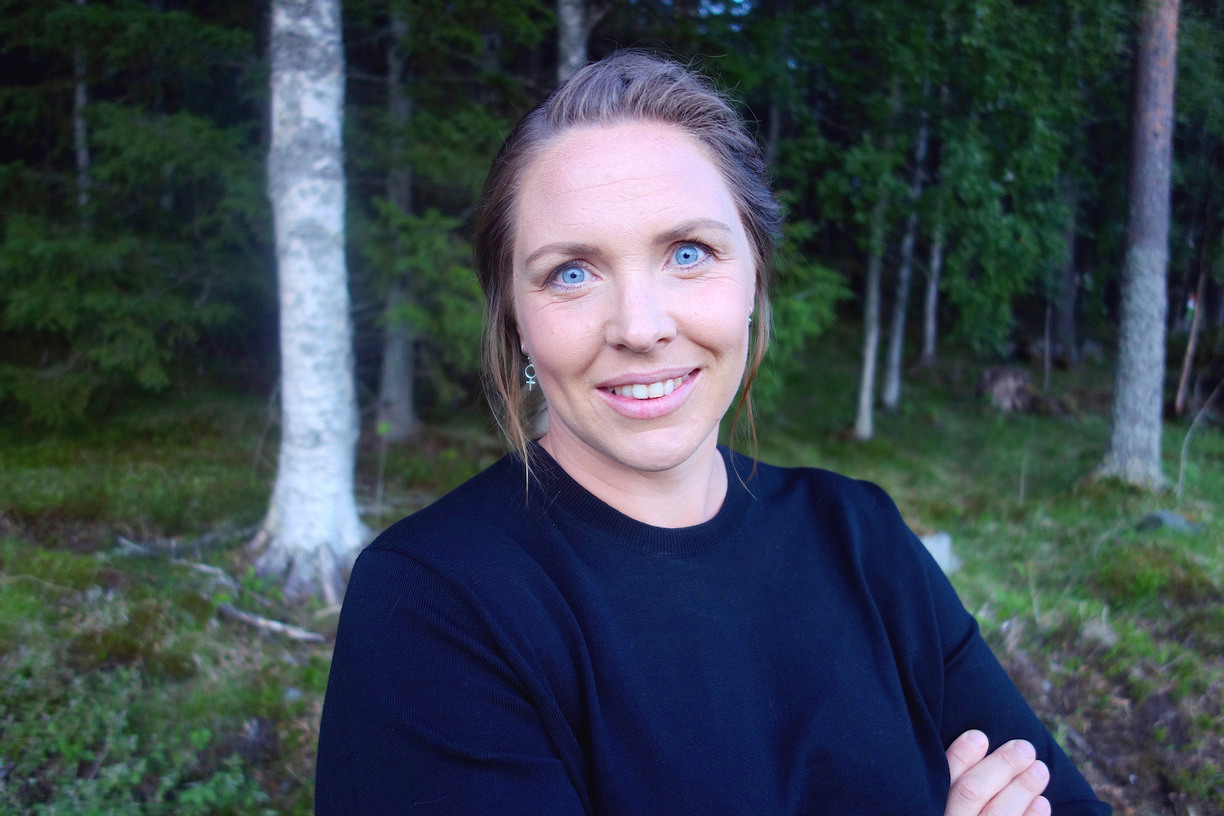 Maria Johansson standing in front of trees in the forest smiling to the camera