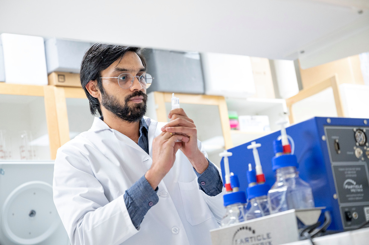 Man in lab coat inspecting vials of saliva samples