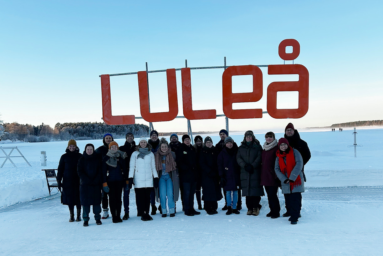 En grupp människor på is med Luleå-skylt bakom