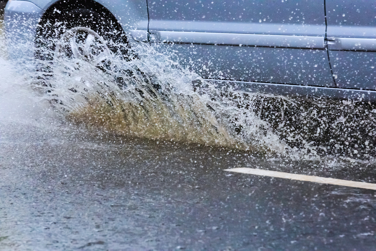 Närbild av bakdäcket av en bil som kör genom en vattenpöl